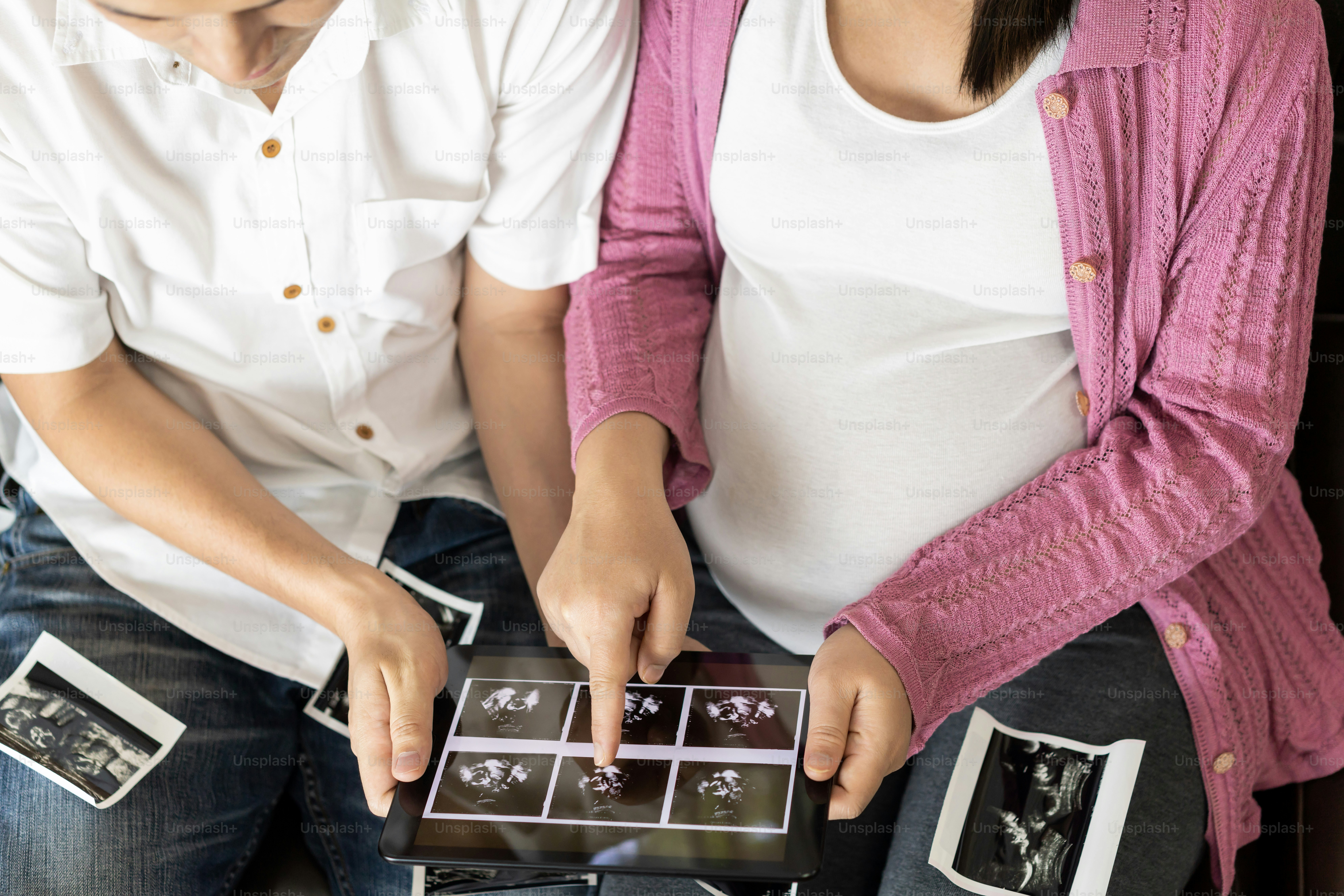 妊婦と男性がタブレットで超音波画像を見ている