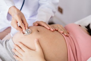 La donna incinta felice visita il medico ginecologo in ospedale o in clinica medica per il consulente di gravidanza. Il medico esamina la pancia incinta per il controllo sanitario del bambino e della madre. Concetto di ginecologia.
