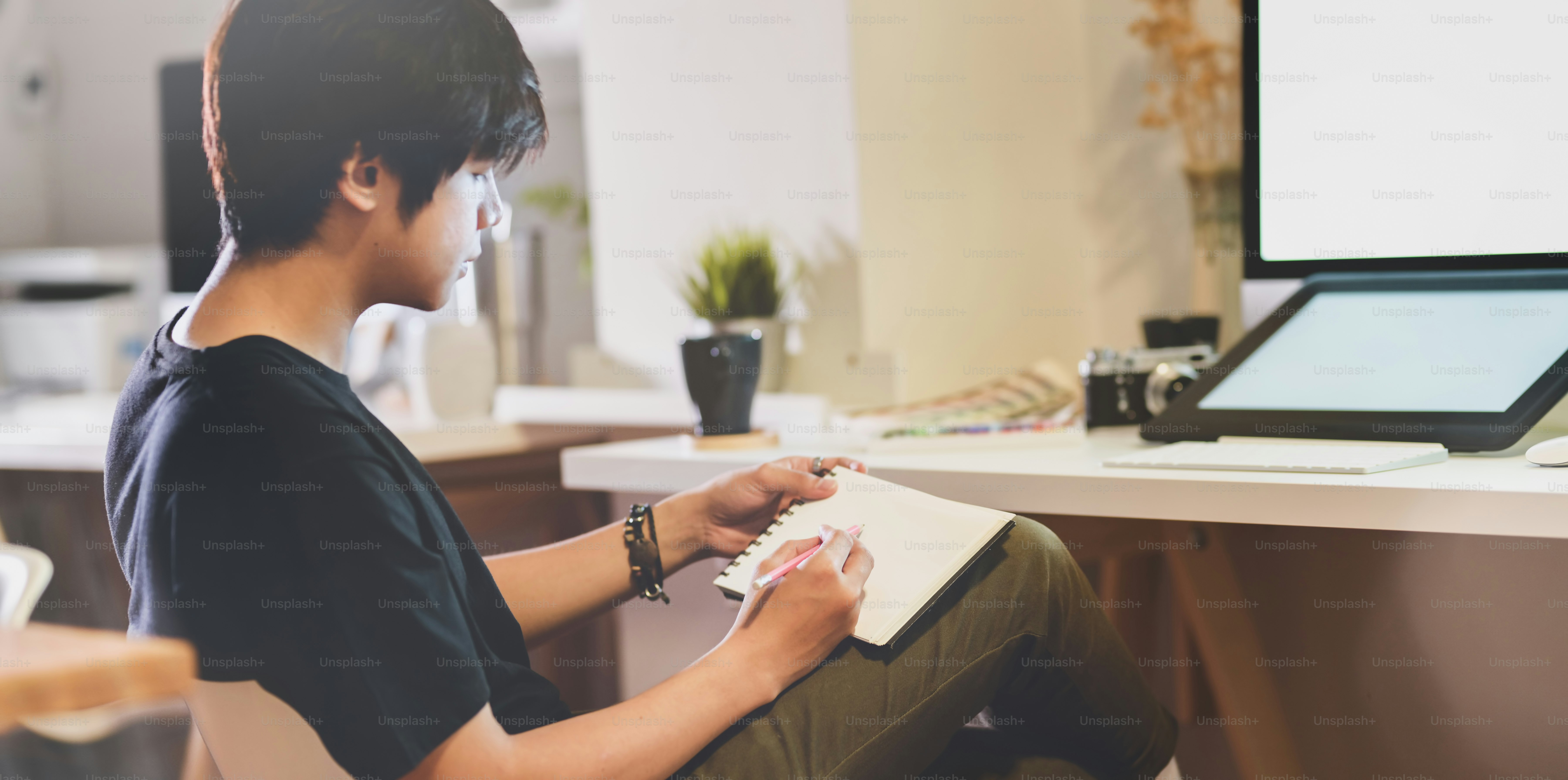 Close-up view of motivated photographer writing his ideas in his workplace