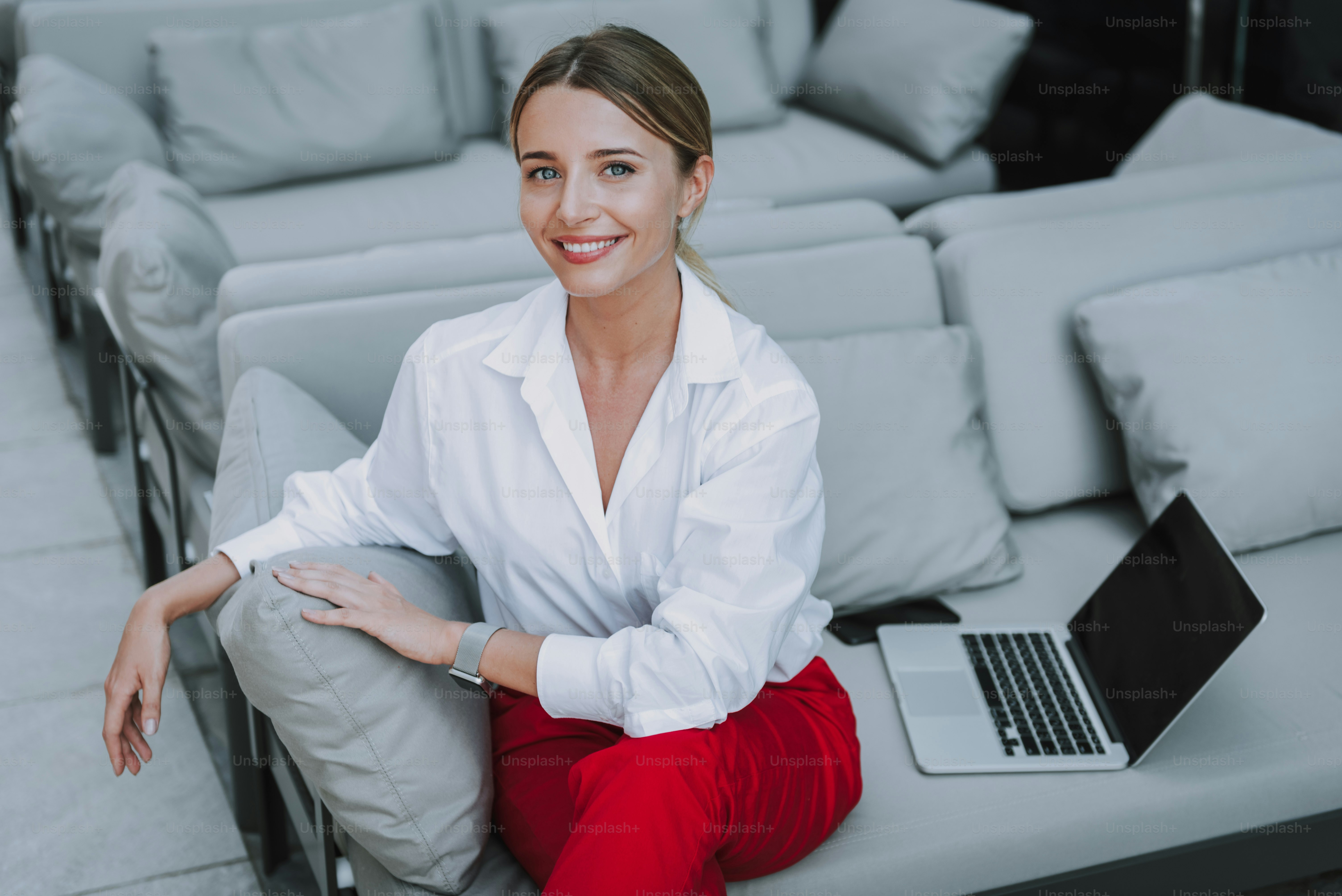 High angle of pretty smiling lady looking at camera while sitting near ...