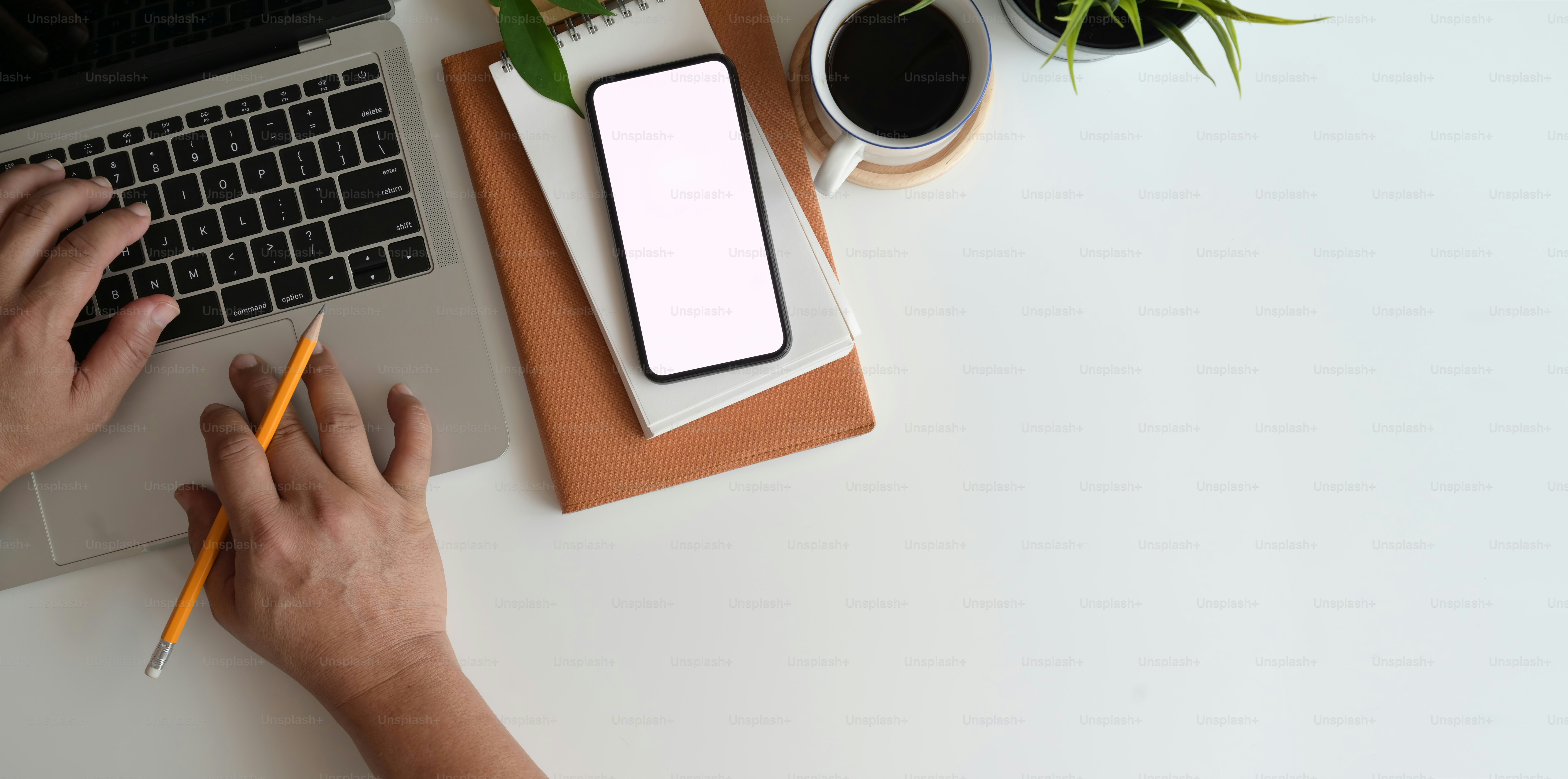 Draufsicht des Mannes, der Laptop auf weißem Schreibtisch mit leerem Bildschirm Smartphone und Kopierplatz tippt