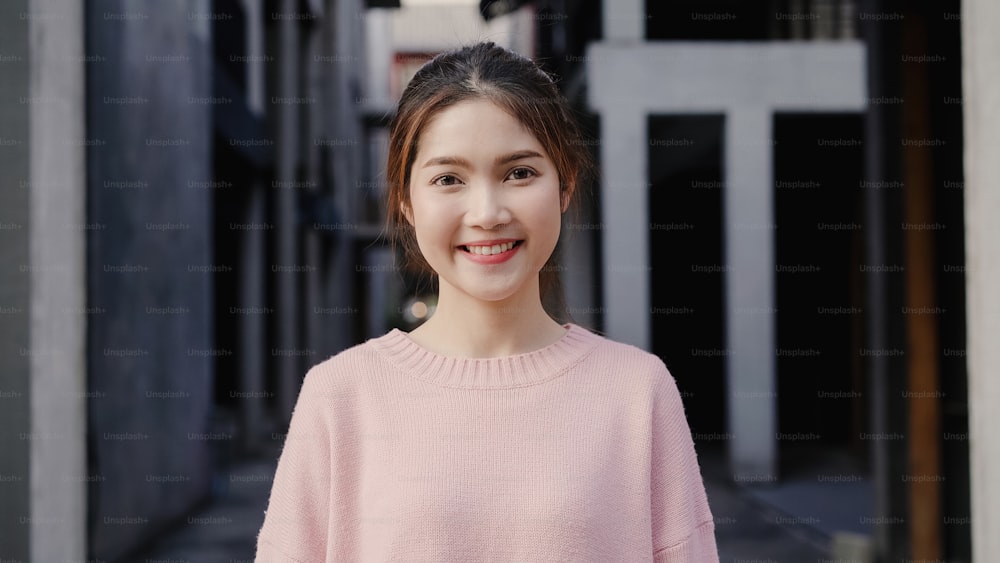 Fröhliche schöne junge asiatische Frau, die glücklich ist, in die Kamera zu lächeln, während sie in Chinatown in Peking, China, reist. Lifestyle Rucksack touristisches Reiseurlaubskonzept. Porträt mit Blick in die Kamera.