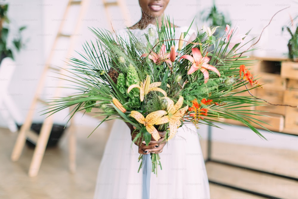 스튜디오에서 열대 꽃다발을 들고 있는 아름다운 아프리카계 미국인 신부.