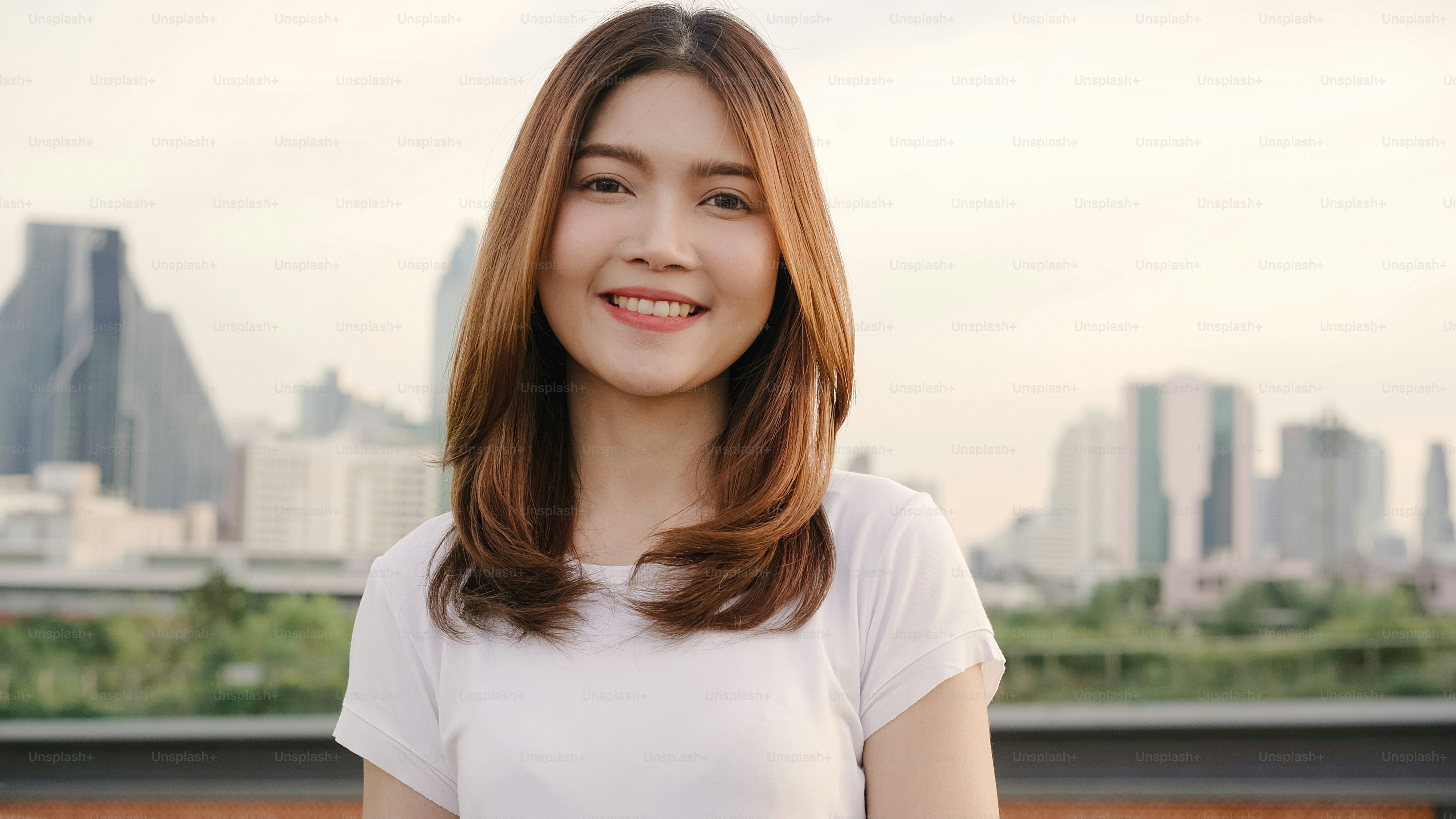 Cheerful beautiful young Asian woman feeling happy smiling to camera while traveling on the street at downtown city. Lifestyle backpack tourist travel holiday concept. Portrait looking at camera.