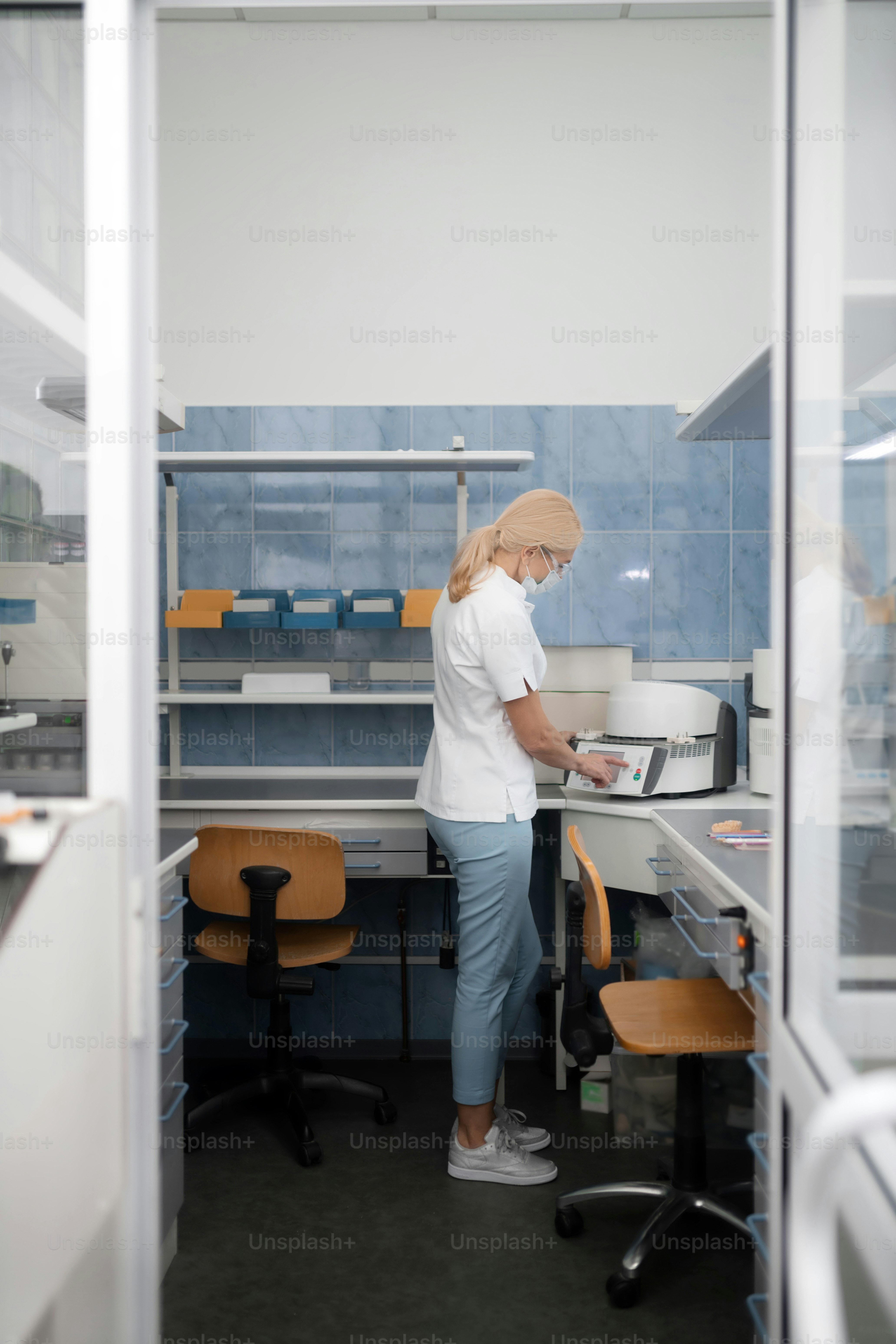 Making tooth crowns. Focused dental prosthetic technician wearing