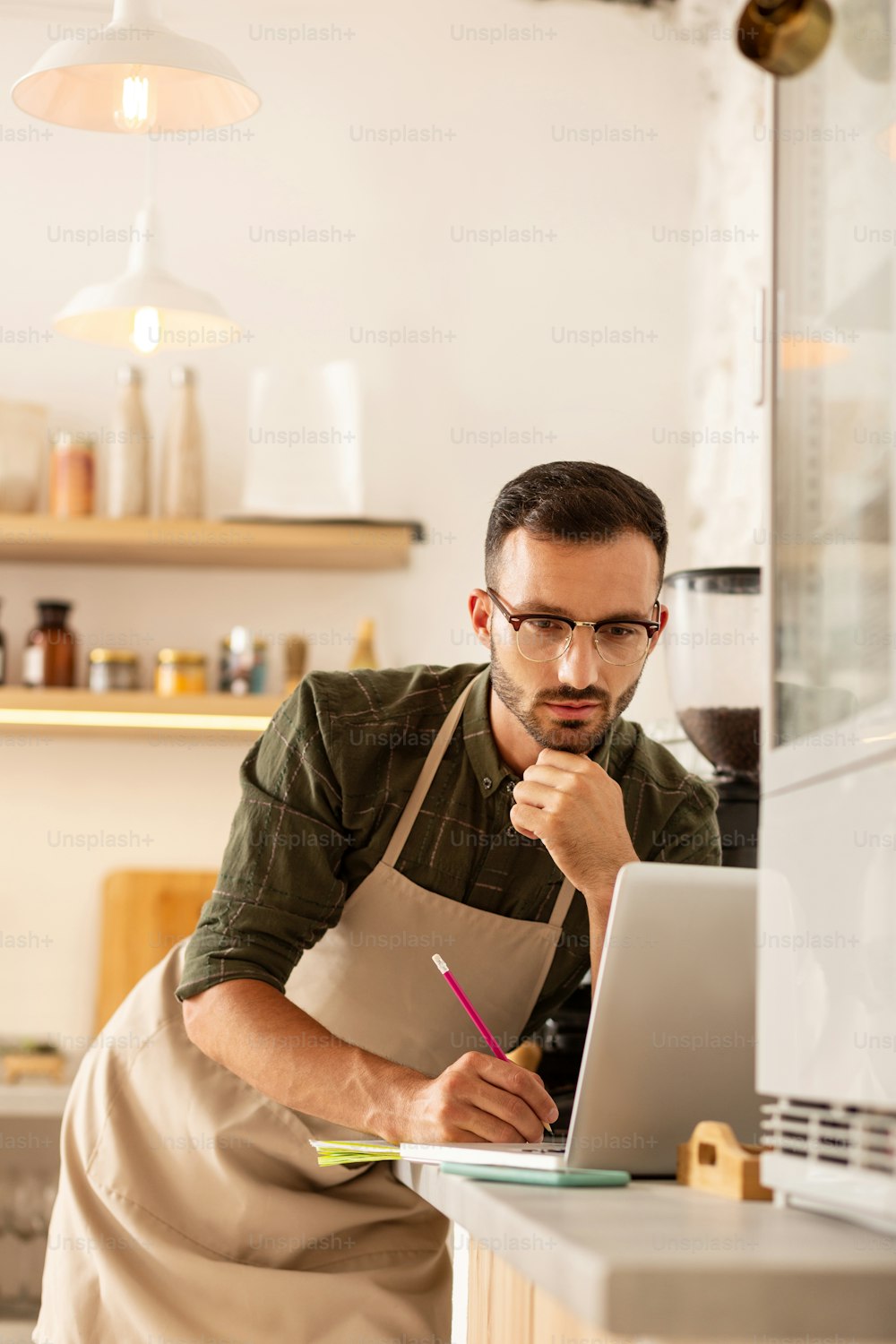 Hombre de negocios que se siente ocupado. Hombre de negocios de ojos oscuros dueño de una cafetería que se siente ocupado mientras pide café en línea