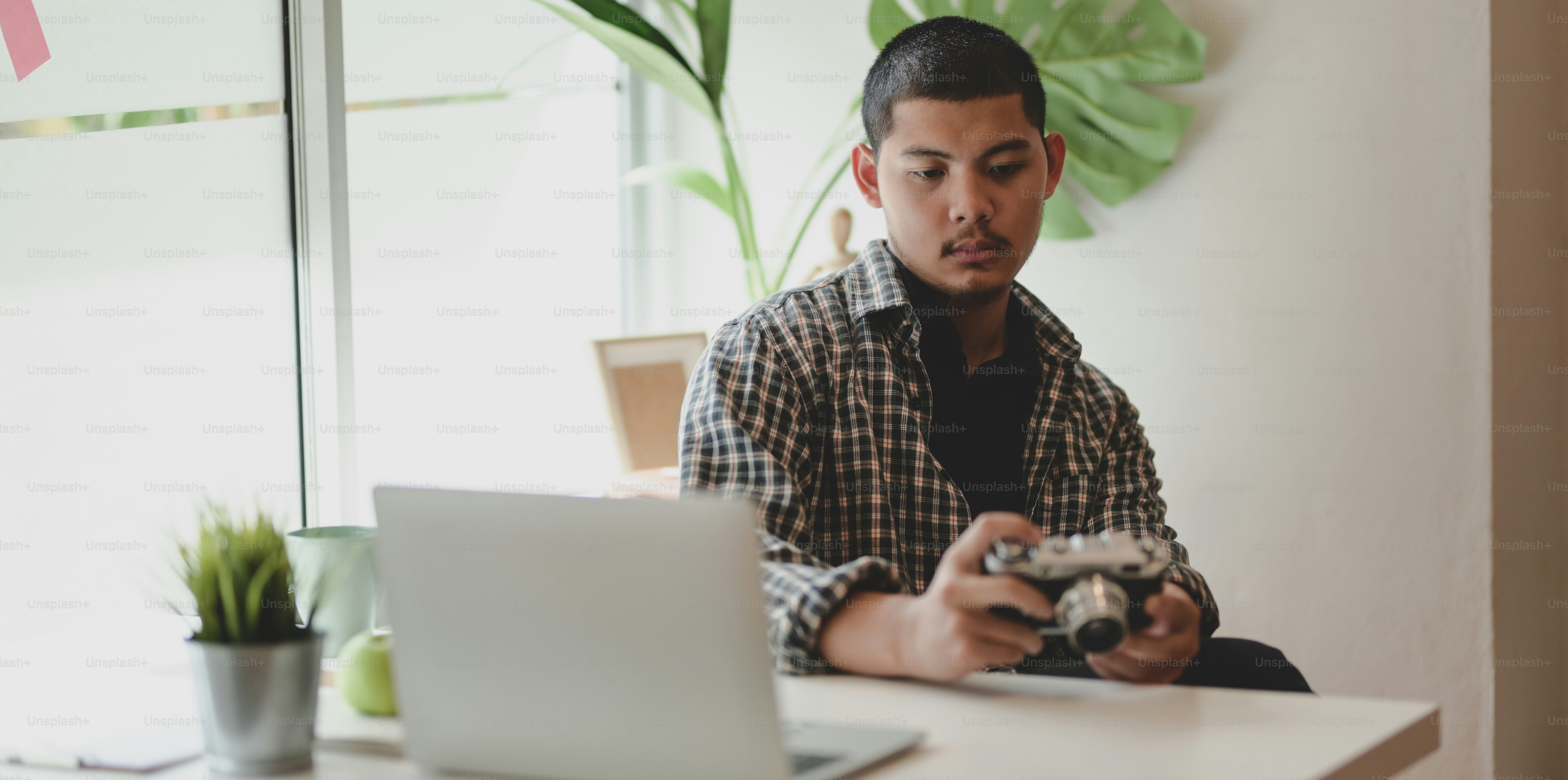 Joven fotógrafo profesional revisando su cámara en un lugar de trabajo mínimo
