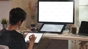 Hinter dem jungen kreativen Mann arbeitet er an Tablet und Stift am Kreativstudio.