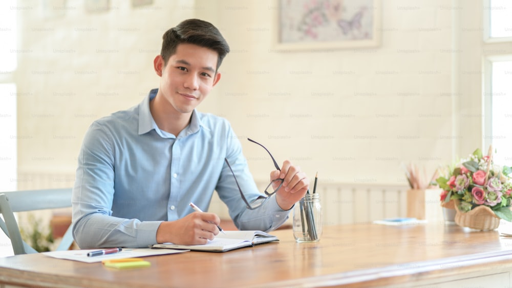 Young businessman smiling confidently at the camera while sitting in modern office room