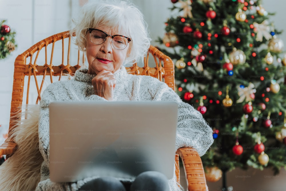 Gray-haired female looking thoughtfully at the screen stock photo