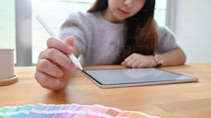 그래픽 디자이너 작업에서 펜을 사용하여 색상을 선택하는 젊은 창조적인 여성.