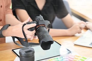Gros plan motivé de photographes vérifiant leur appareil photo dans leur lieu de travail moderne.