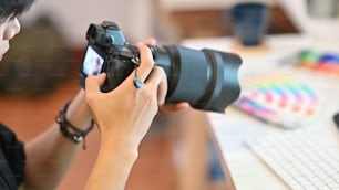 Primo piano Cameraman che controlla con la fotocamera professionale Fotografo fotografico che lavora sul posto di lavoro creativo.