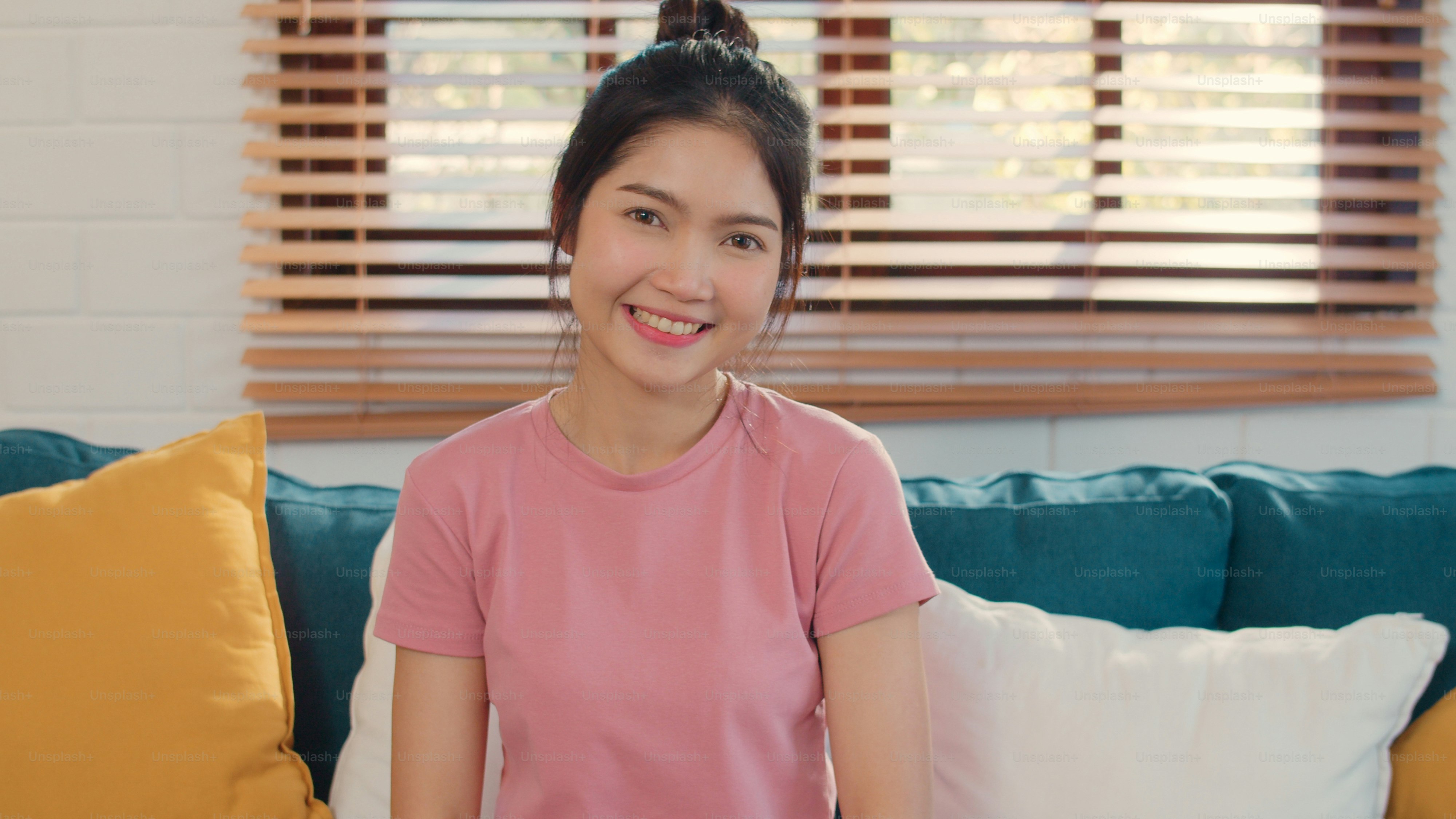 Portrait Asian Chinese woman feeling happy smiling at home. Japanese girl relax toothy smile looking to camera while lying sofa in living room at home in the morning concept.