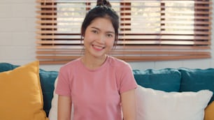 Portrait Asian Chinese woman feeling happy smiling at home. Japanese girl relax toothy smile looking to camera while lying sofa in living room at home in the morning concept.