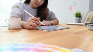 Mujer creativa joven que usa el color de selección de la pluma en el trabajo de diseñador gráfico.