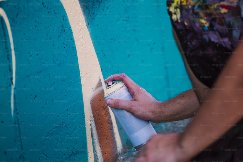 Artista de rua pintando grafite colorido na parede genérica - Conceito de arte moderna com cara urbano realizando e preparando murais ao vivo com spray de aerossol multicolorido