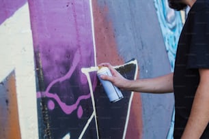 Straßenkünstler malen bunte Graffiti auf generische Wand - Modernes Kunstkonzept mit urbanem Typ, der Live-Wandgemälde mit mehrfarbigem Aerosolspray aufführt und vorbereitet