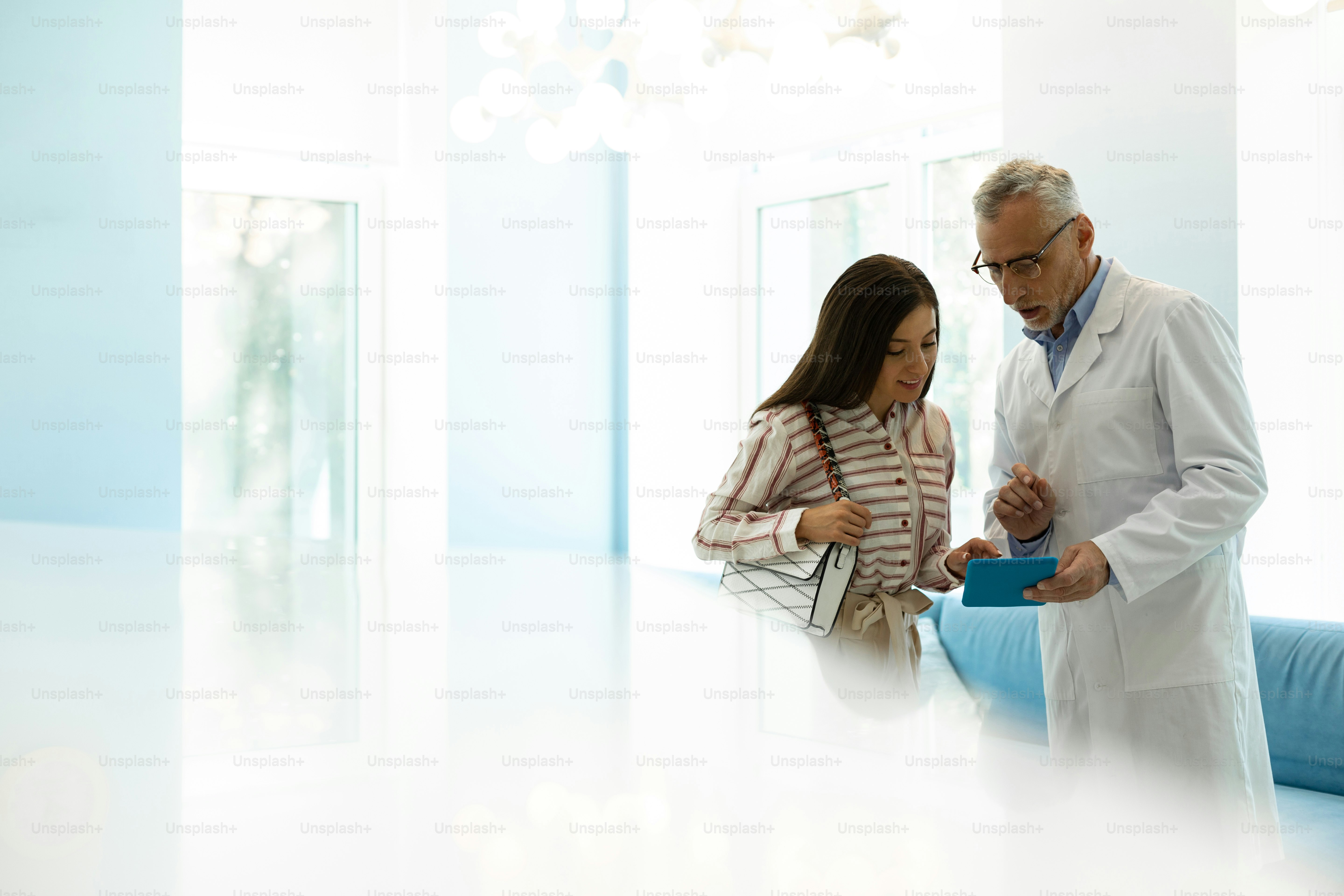 Have a look. Attentive senior medical worker wearing lab coat while communicating with his patient