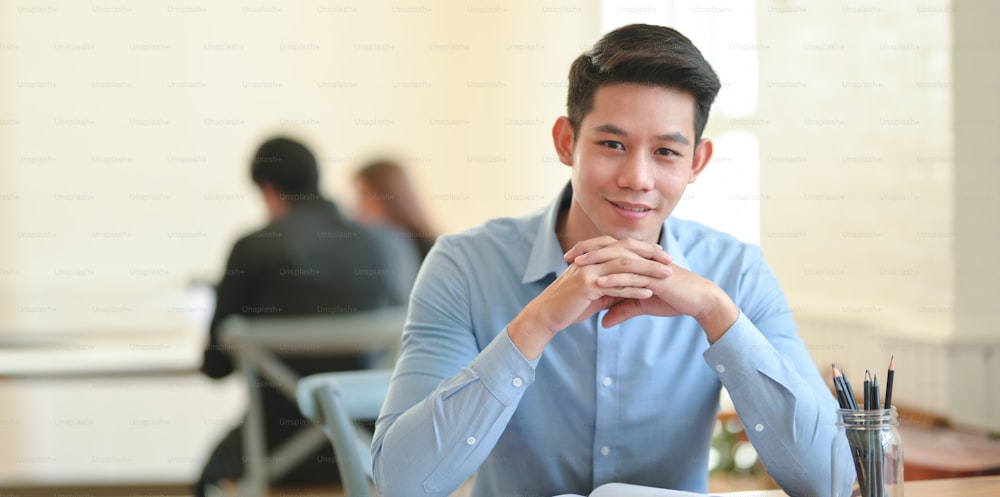 Young businessman smiling confidently at the camera while sitting in modern office room