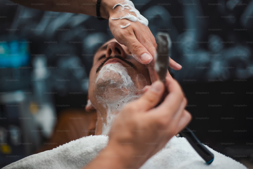 専門の理髪師の手にあるかみそり。理髪店で男を剃る床屋、接写。剃毛をしている男の口ひげ