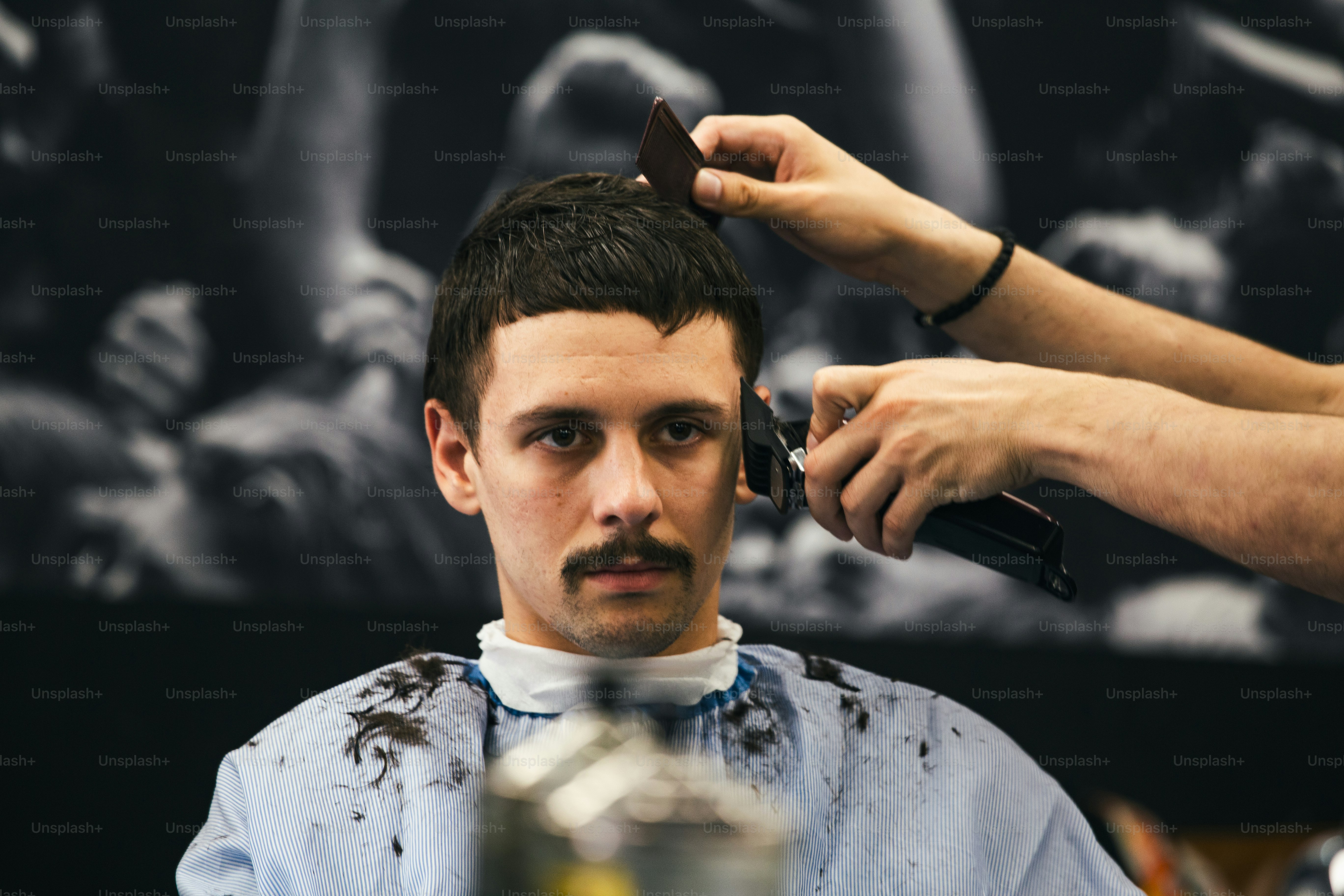 Hombre que se corta el pelo de moda en la peluquería. Peluquero masculino que atiende al cliente, haciendo cortes de pelo con máquina y peine.
