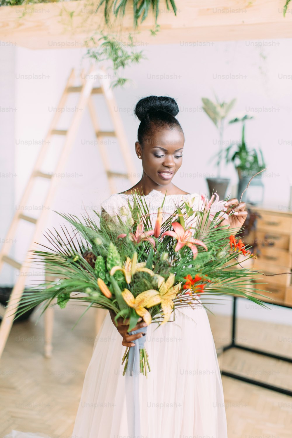 아름 다운 어두운 피부 신부입니다. 스튜디오에서 열대 꽃다발을 들고 있는 아름다운 아프리카계 미국인 신부.