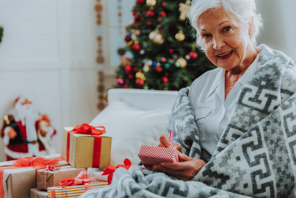 Smiling old lady preparing Christmas gifts stock photo