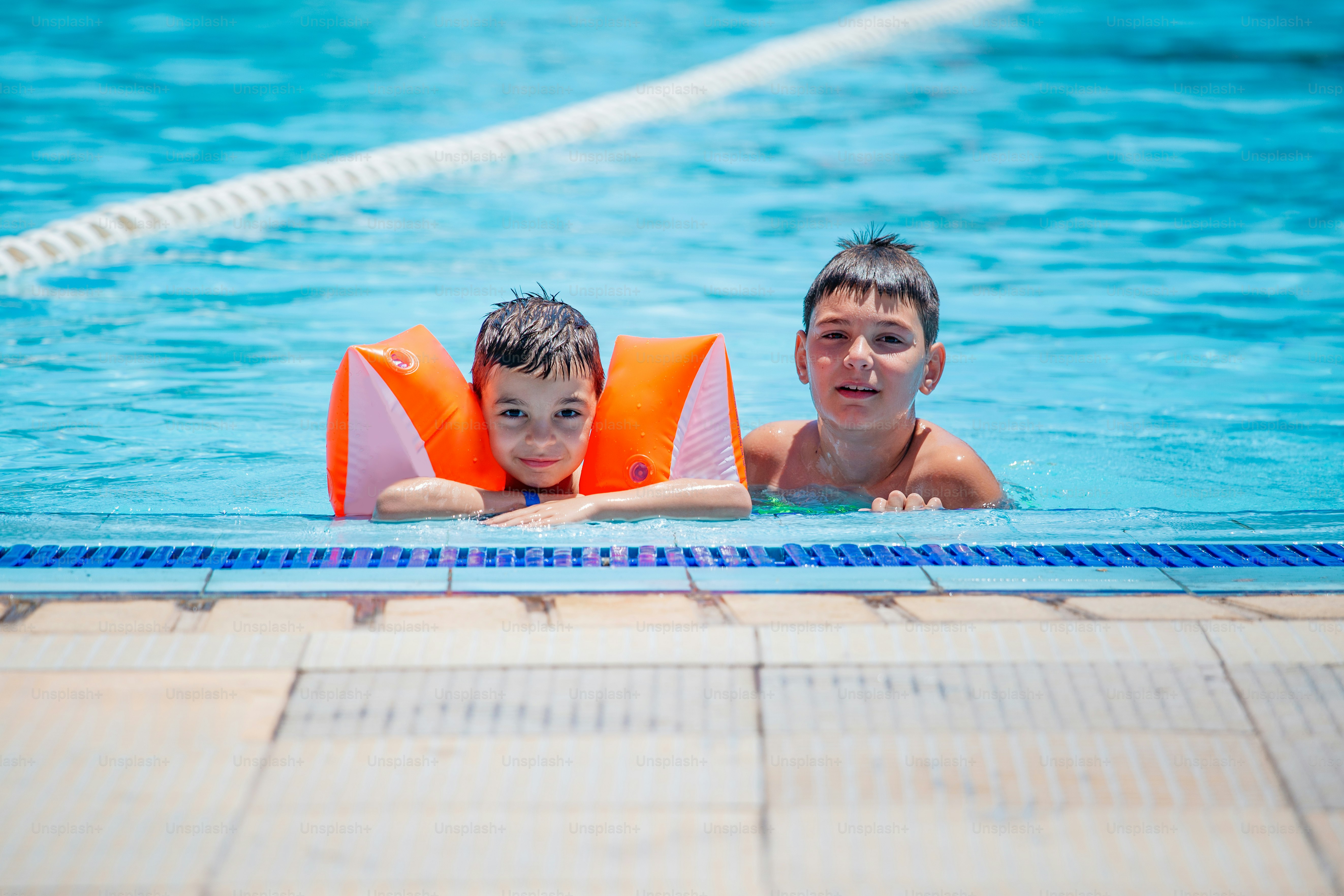 Older brother and younger brother swim in the outdoor children's pool