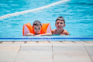 Älterer Bruder und jüngerer Bruder schwimmen im Kinderbecken im Freien