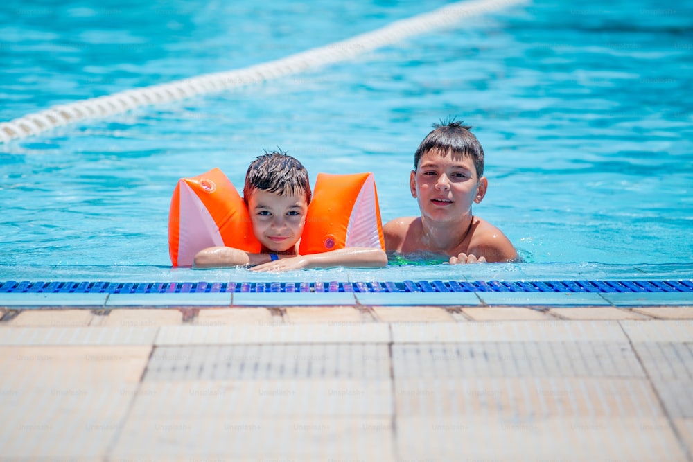 Le frère aîné et le frère cadet nagent dans la piscine extérieure pour enfants