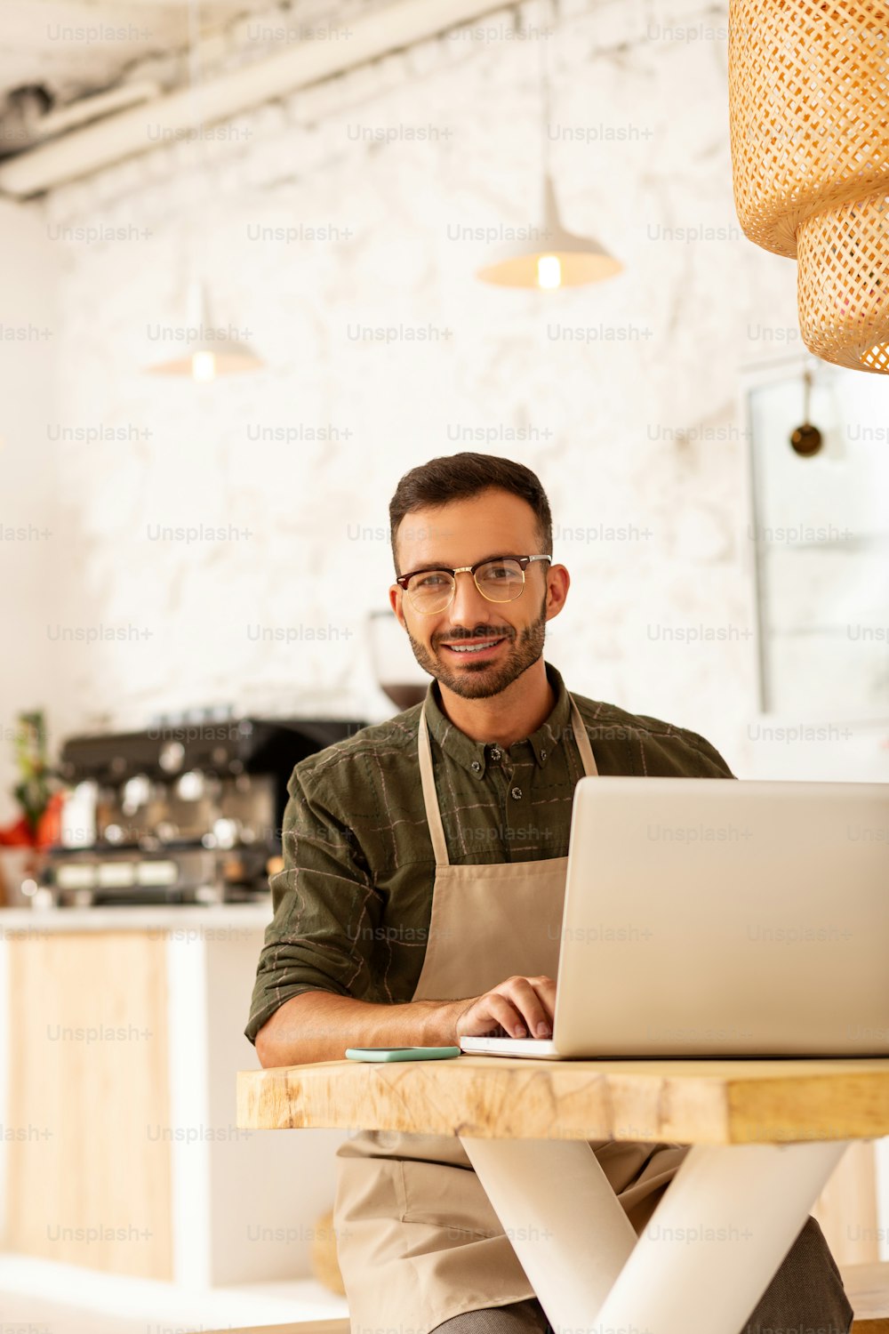 Owning coffee shop. Entrepreneur owning coffee shop sitting at the table with laptop
