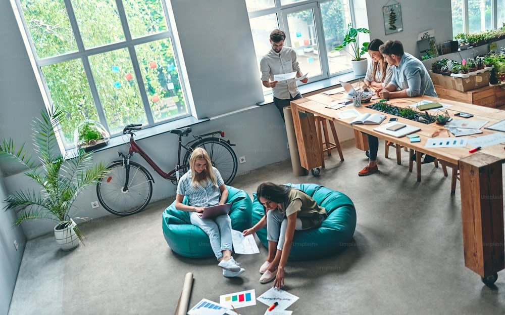 Eine Gruppe junger Geschäftsleute arbeitet in einem modernen Büro zusammen. Kreative Menschen mit Laptop, Tablet, Smartphone, Notebook. Erfolgreiches Hipster-Team im Coworking. Freiberufler.