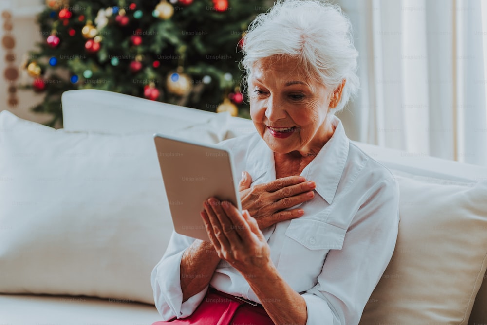 Smiling elderly woman looking on tablet screen stock photo