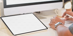 Close-up view of young businessman working on his project with blank screen tablet on white table