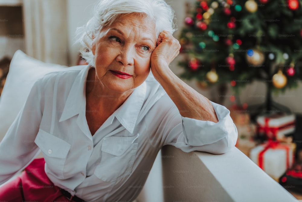 Old lady looking aside thoughtfully at home stock photo