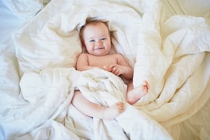 Cute little girl playing on bed. Happy kid having fun in nursery.