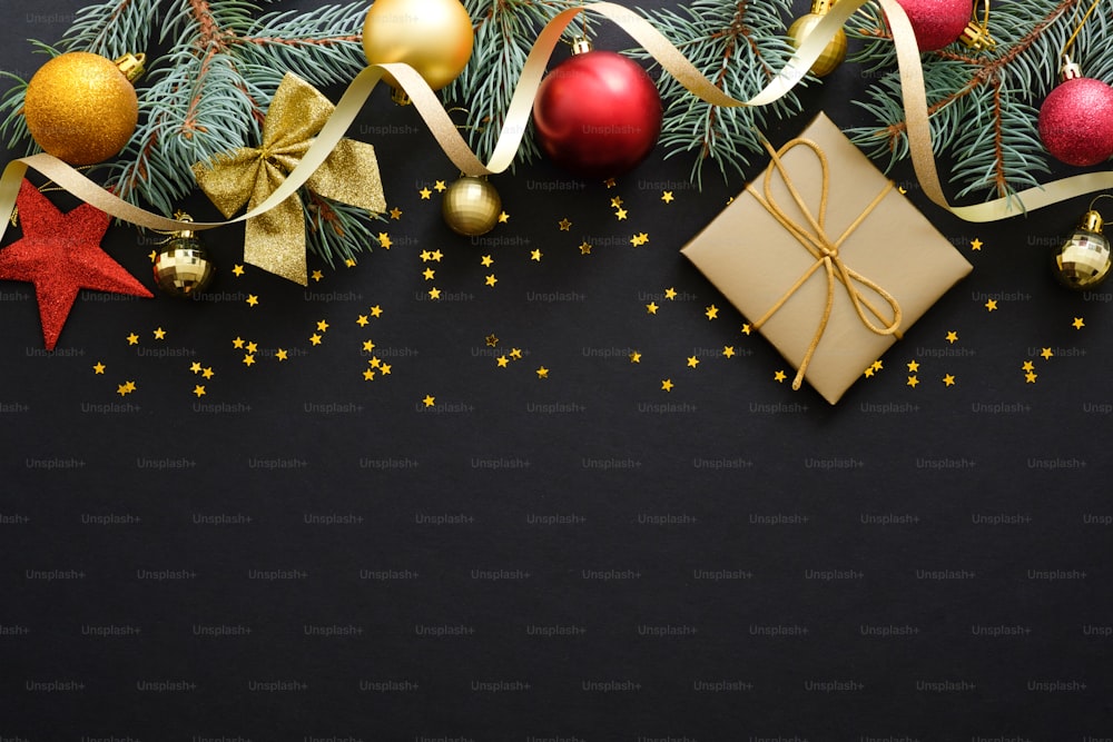 モミの木の枝、装飾、赤と金のつまらないものとクリスマスの黒い背景。ギフトボックス、紙吹雪。クリスマス、冬休み、新年のコンセプト。フラットレイ、上面図。コピースペース。クリスマスバナー
