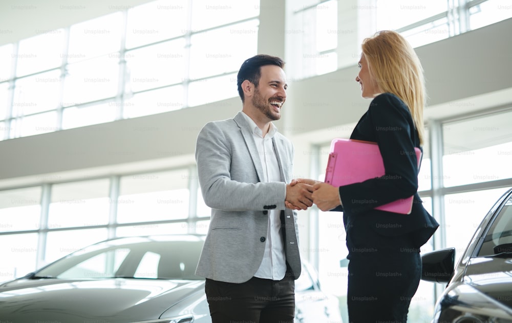 Professional woman salesperson during work with customer at car dealership.