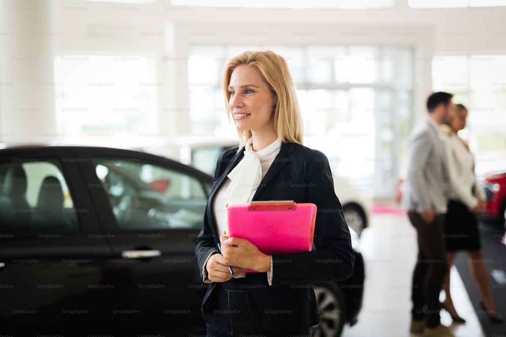 Portrait of young happy and success saleswoman in car dealership