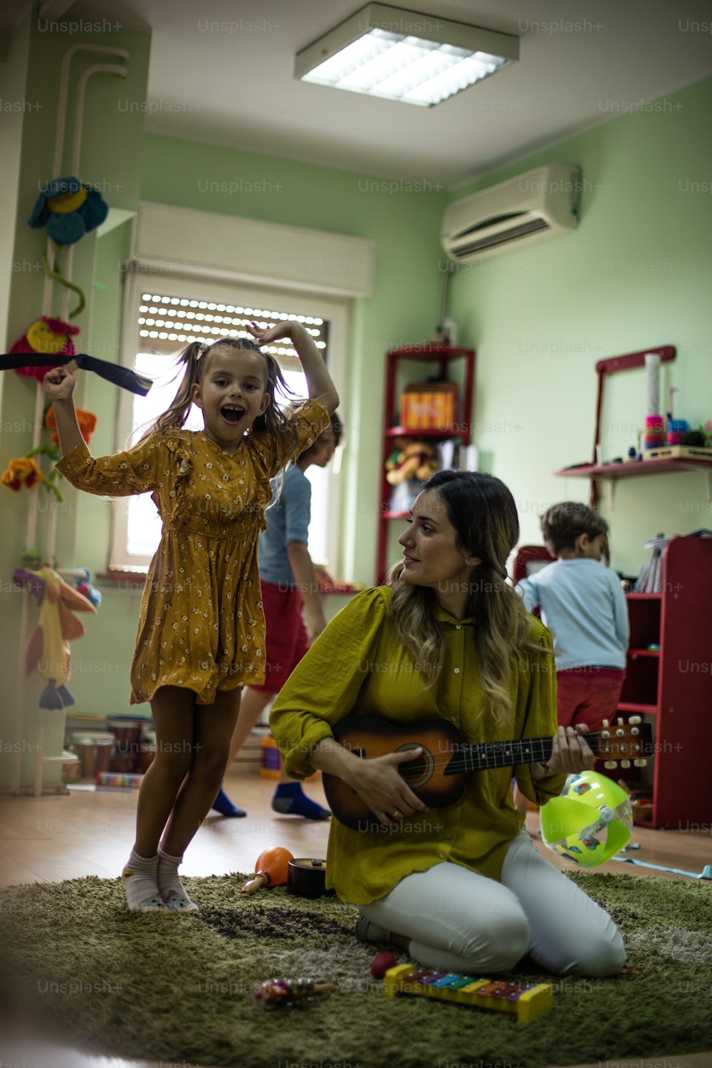 La guitarra libera sonidos maravillosos para el baile. Niños con maestra en preescolar.