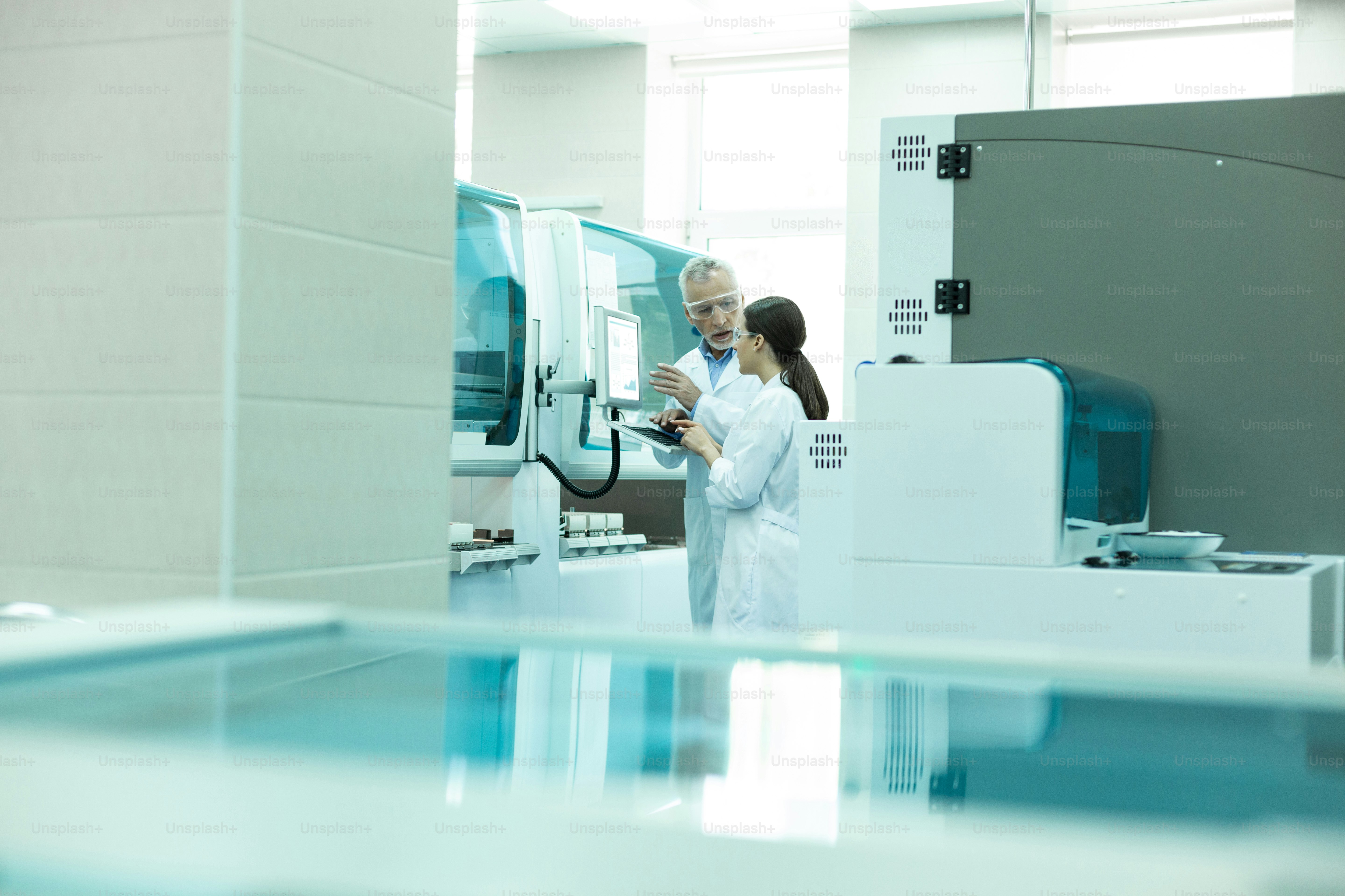 Modernes Labor. Ernsthafter bärtiger medizinischer Arbeiter trägt Schutzbrille bei der Vorführung von Ausrüstung