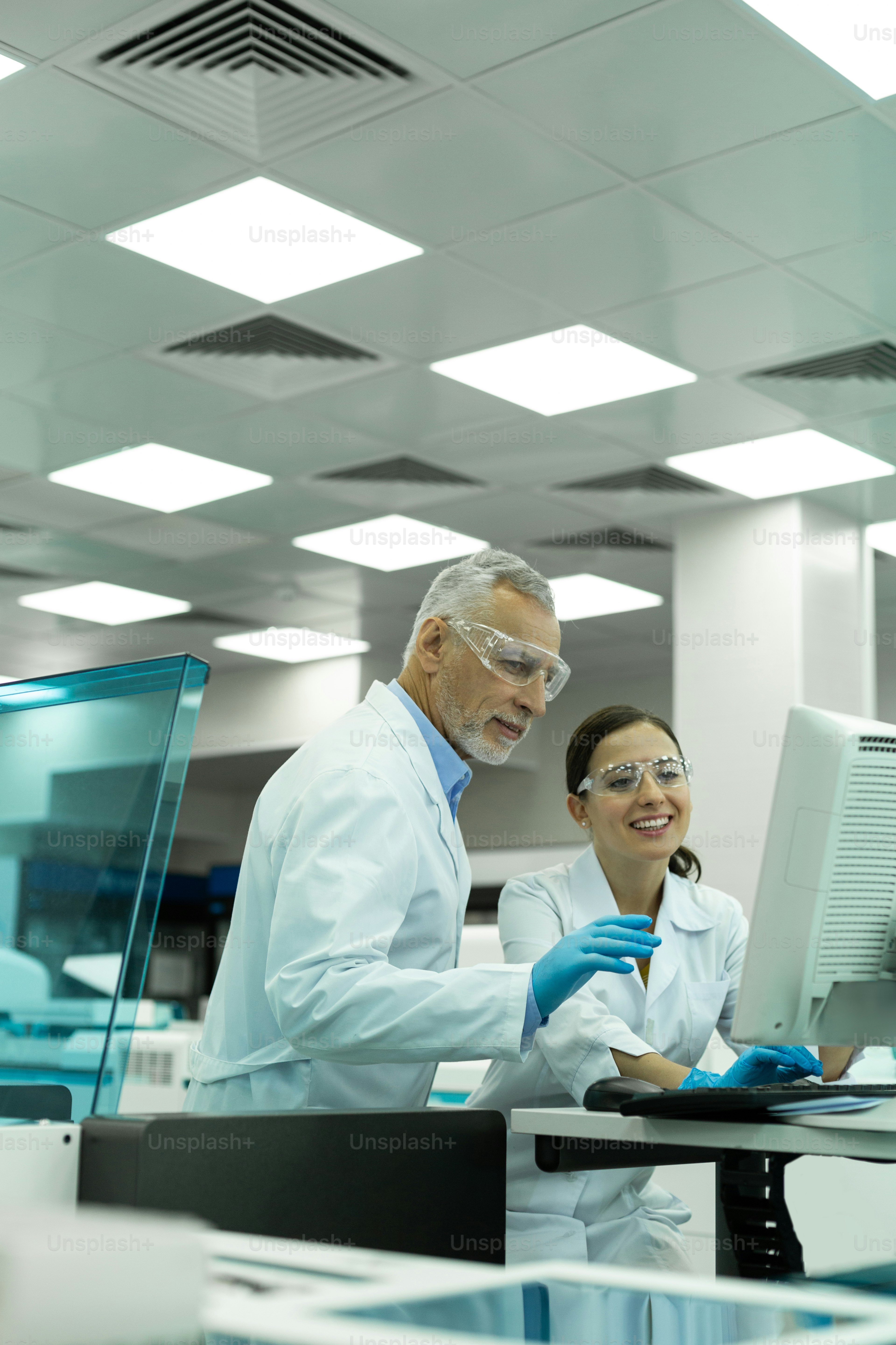 Betriebsklima. Erfreute junge Frau, die ein Lächeln im Gesicht behält, während sie auf den Computer starrt