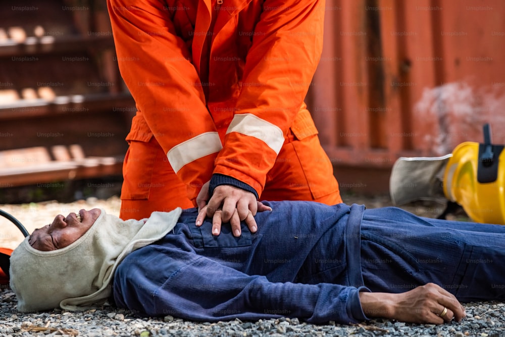 Disparo medio de un bombero con traje de bomberos en servicio de rescate de seguridad para ayudar a detener la respiración de un hombre de ataque cardíaco dentro de las instalaciones en llamas mediante RCP de emergencia de primeros auxilios. Concepto de seguridad, rescate y cuidado de la salud.