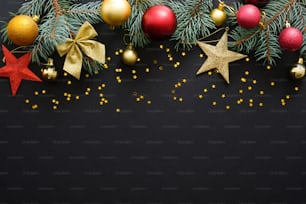 Christmas holiday composition. Festive Christmas decorations, baubles, fir tree branches, confetti star on dark black background with copy space. Banner mockup, postcard. Flat lay, top view, overhead