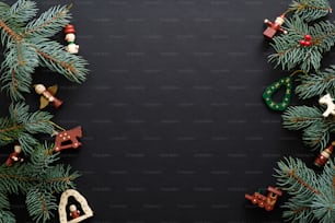 Fondo navideño negro con adornos de madera hechos a mano y ramas de abeto. Celebración de vacaciones de Navidad, invierno, concepto de Año Nuevo. Maqueta de banner de Navidad, plantilla de tarjeta de felicitación.