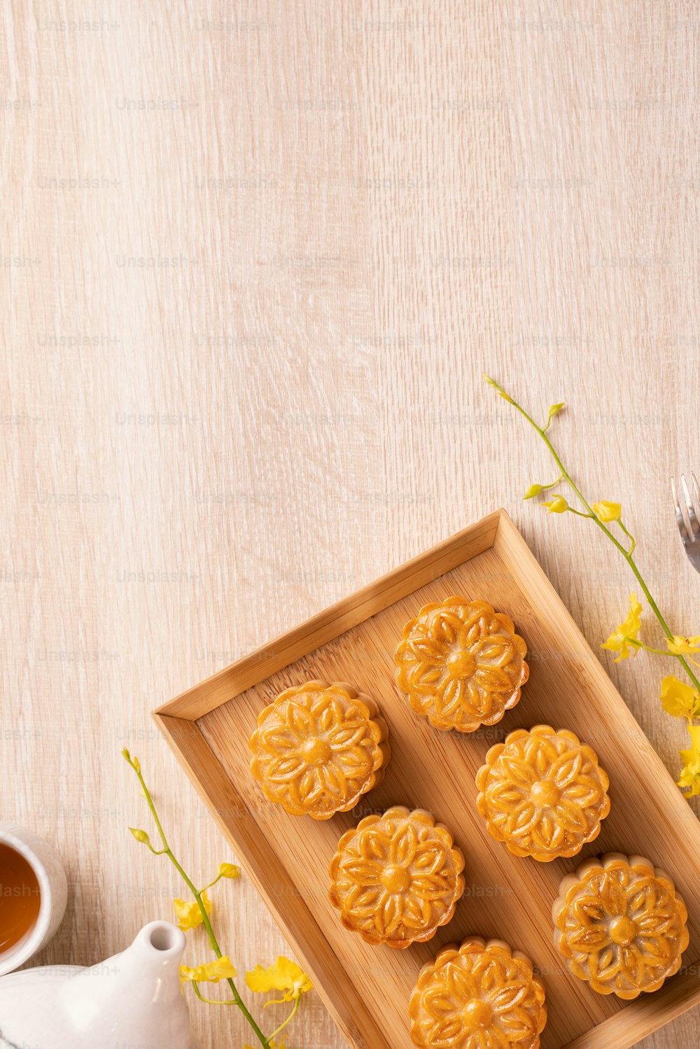 Moon cakes with tea on bright wooden table, holiday concept of Mid-Autumn festival traditional food layout design, top view, flat lay, copy space.