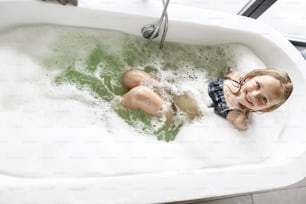Smiling girl having fun bathing in the bath stock photo