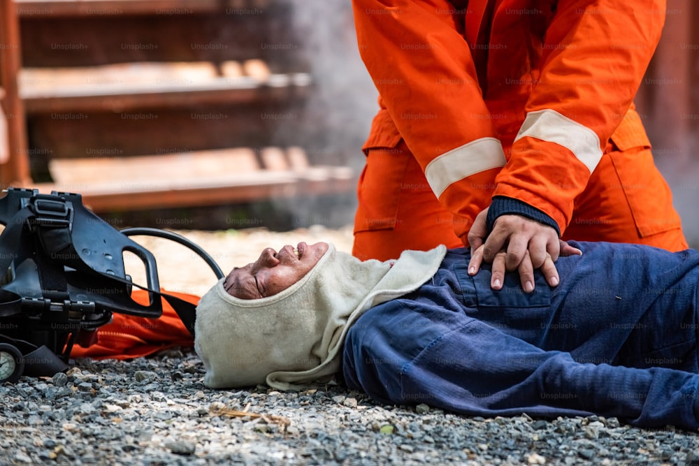 Tiro médio de bombeiro em traje de incêndio em serviço de resgate de segurança ajuda a parar de respirar homem de ataque cardíaco dentro de instalações em chamas por RCP de emergência de primeiros socorros. Conceito de segurança, resgate e saúde.