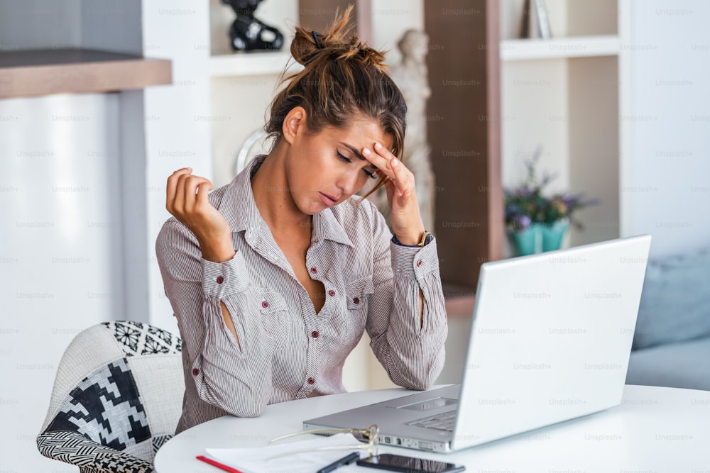 Feeling exhausted. Frustrated young woman looking exhausted while sitting at her working place and carrying her glasses in hand